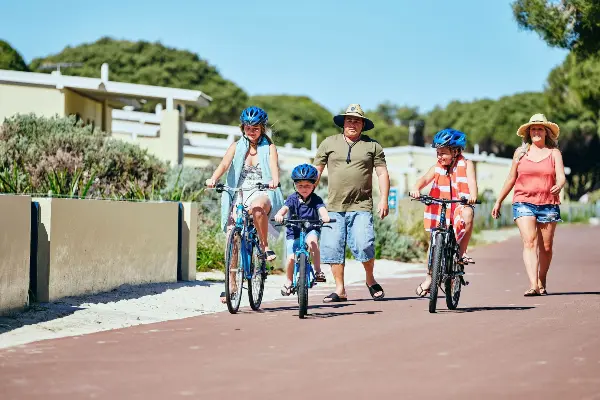 Family riding bikes in front of accommodation at Rottnest Island.