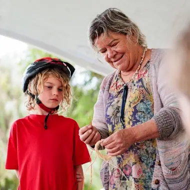 A boy being taught how to weave.