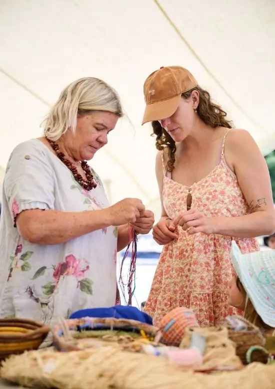 Two people weaving thread.