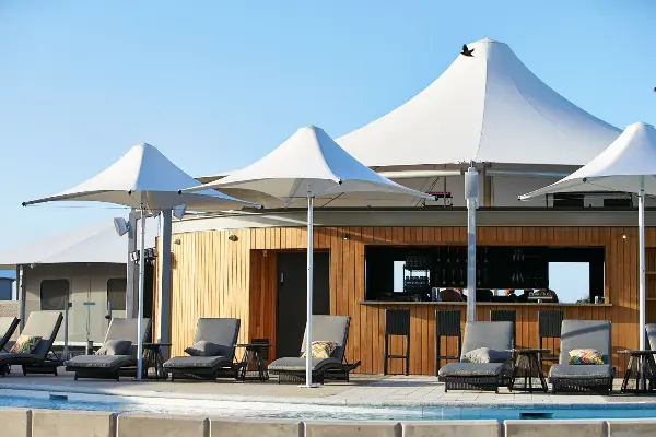 Pool area with grey sun lounges and white umbrellas.