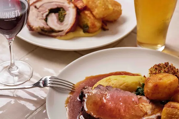 Two plates of roast with beer and red wine.