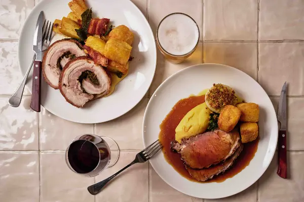 Two plates of roast with wine and beer.