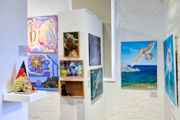 A selection of beautiful Aboriginal artworks from the Connections to Wadjemup exhibition on white textured walls.