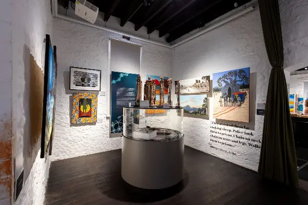 A selection of beautiful Aboriginal artworks from the Connections to Wadjemup exhibition on white textured walls.