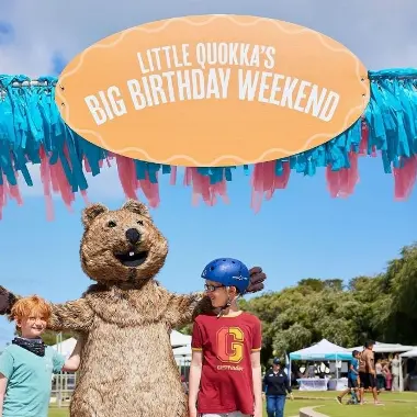 Picture of two children and a Quokka mascot underneath a 
