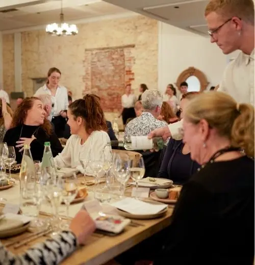 A group talking as wine is poured.