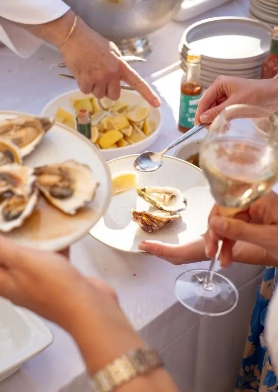 Hands holding a plate oysters and a Glass of white wine.