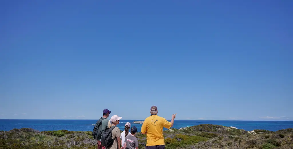 A Volunteer from the Rottnest Island Volunteer Guides showing a family the coastline on Rottnest Island