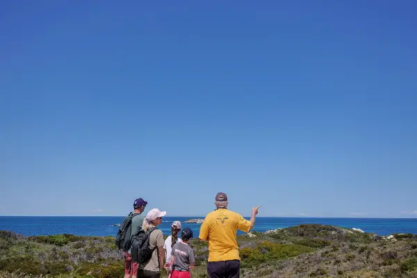 A Volunteer from the Rottnest Island Volunteer Guides showing a family the coastline on Rottnest Island