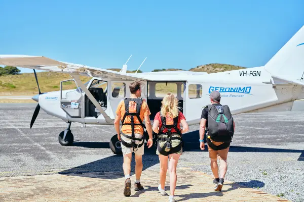 Three people about to climb into a plane for skydiving.
