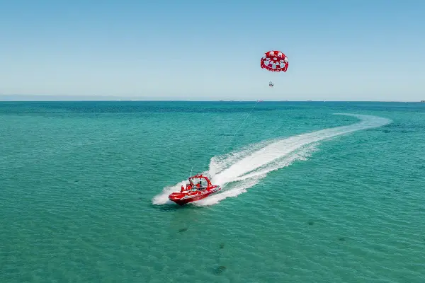 Jet board coasting through blue water, pulling parasail.