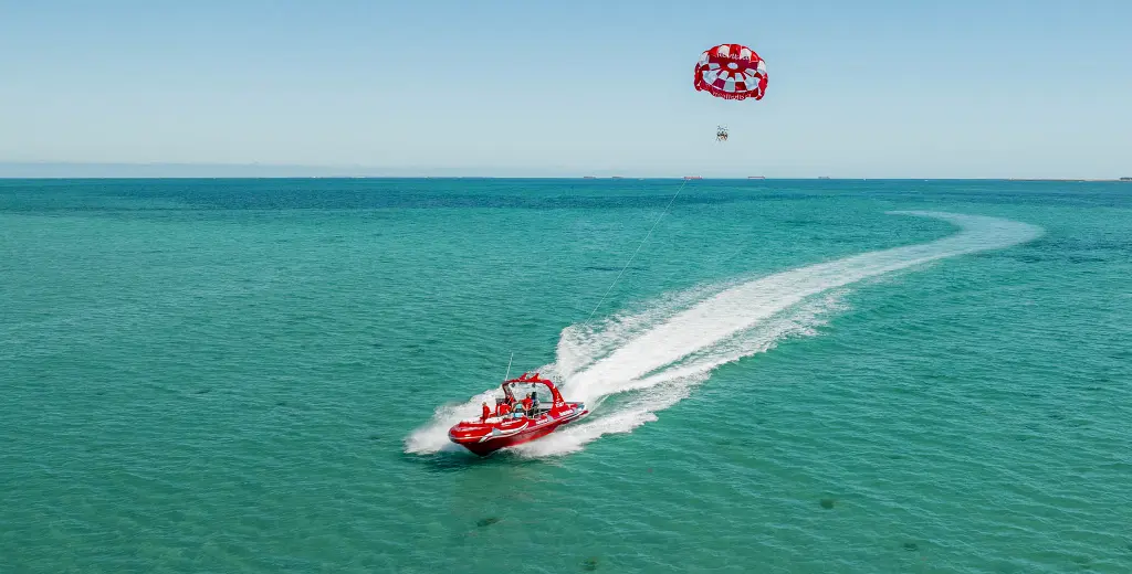 Jet board coasting through blue water, pulling parasail.