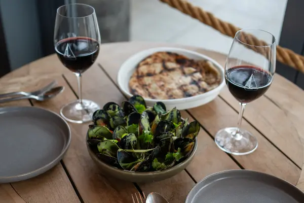 Coconut Green Mussels in the centre of the table with red wine.