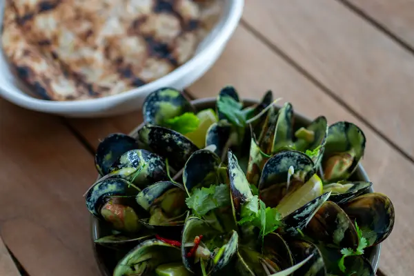 Coconut Green Mussels with flatbread on a table,
