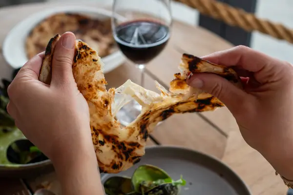 Hands ripping flatbread in half.