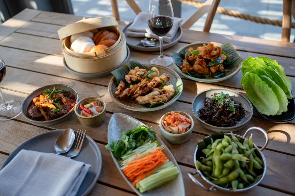 Bamboo basket of steamed bao buns with assorted fillings and toppings on the table
