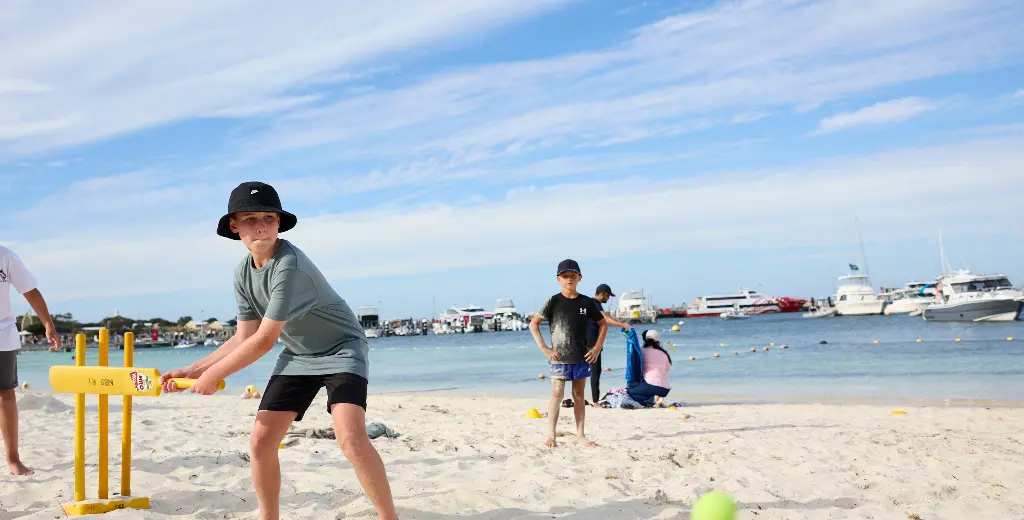 Children play cricket on beach