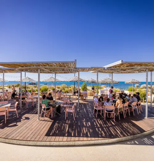 Tables and chairs under shade shelter and on decking outside at Pinky's Rottnest Island