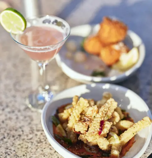 Share plates of food and a pink cocktail