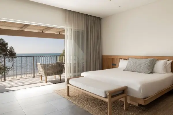 A super king bed next to a balcony with a view of Thomson Bay,