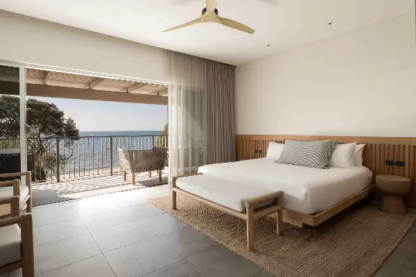 A super king bed next to a balcony with a view of Thomson Bay.