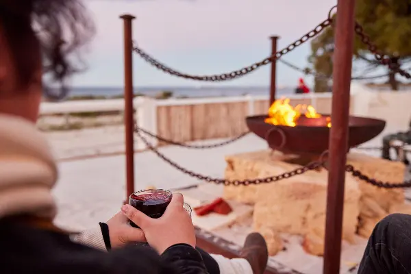 A group of people surrounding a firepit at Samphire Rottnest.