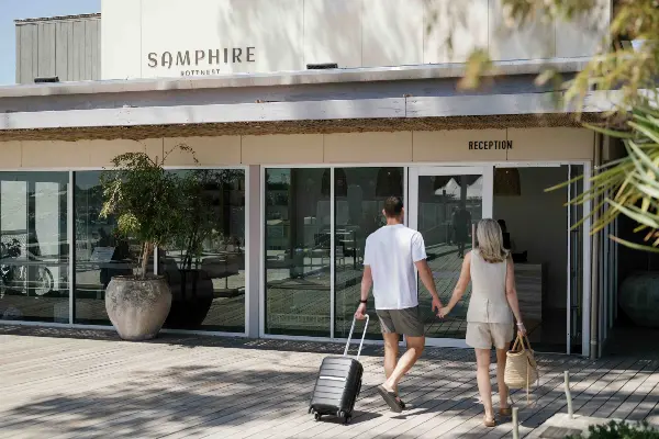 A couple with suitcases walking into Samphire Rottnest.