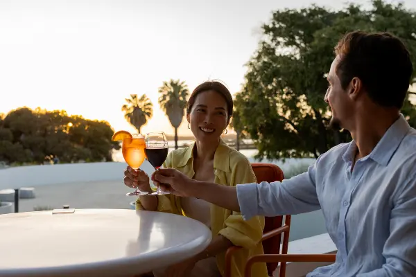 Couple looking at each other and doing a cheers with sunset in background