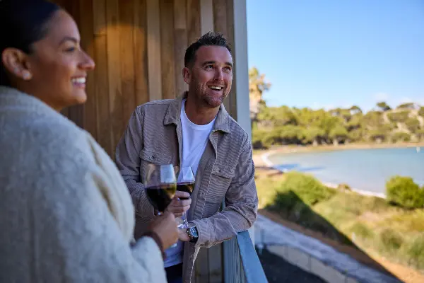 Two people holding wine glasses on a balcony.