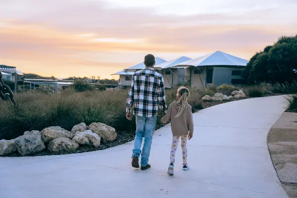 A father and daughter walking between eco tents.
